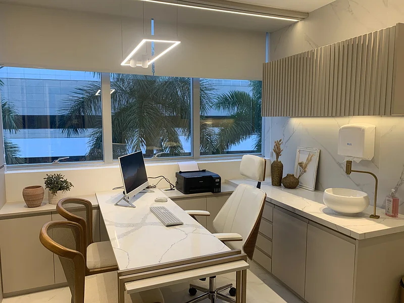 Sala de atendimento com mesa de mármore e janela com vista para as palmeiras