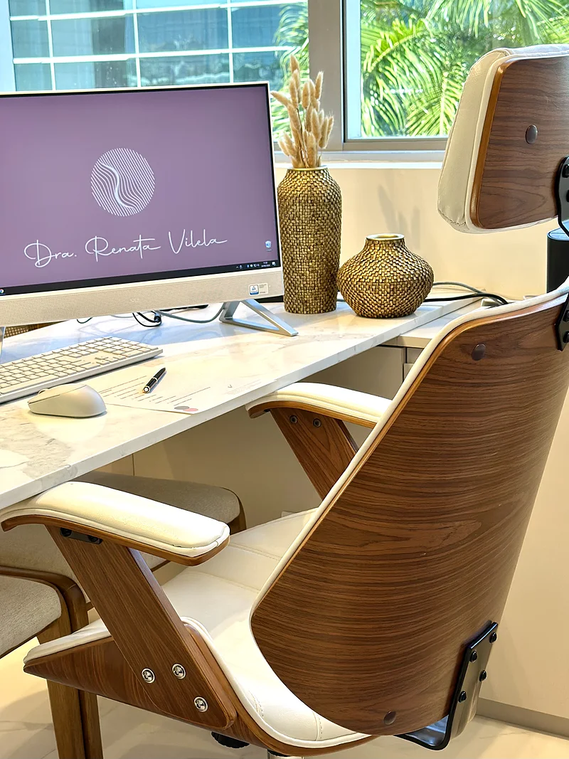 Detalhe da mesa da doutora com o logotipo na tela do computador